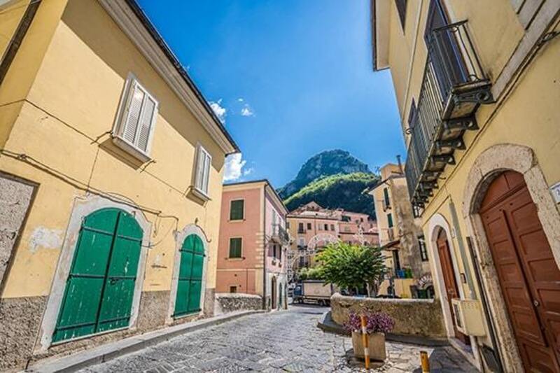 yellow building with green oor opposite yellow buillding with brown door on a cobbled street with blue sky