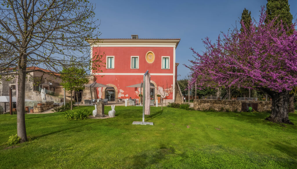 Terracotta hotel surrounded by trees and grass