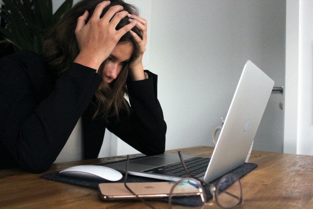 woman leaning over laptop with head in hands